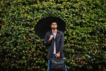 Fashionable tall arab beard man wear on black coat with umbrella